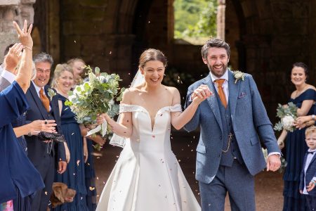 married heterosexual couple leaving the church being showered with confetti and smiling.