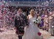 a hetero couple walking through a storm of maroon, white and pink confetti outside Tynecastle football stadium